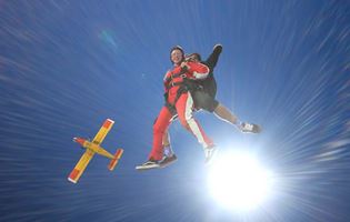 tandem skydivers with plane in background