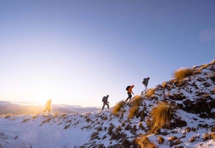 Backpackers from YHA Wanaka walking along snowy ridge at Roys Peak
