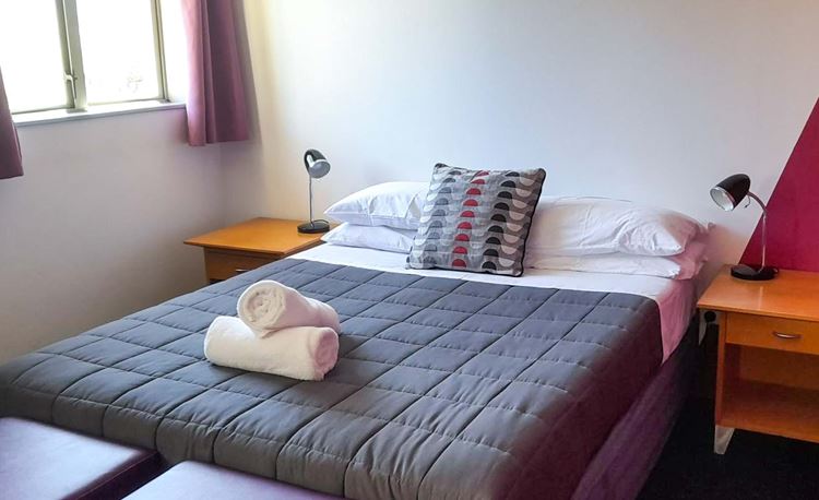 Double room at YHA Nelson set up for couples with double bed and towels.