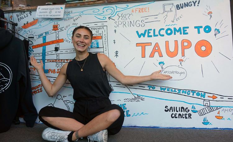 girl sitting in front of welcome sign at local Taupo hostel